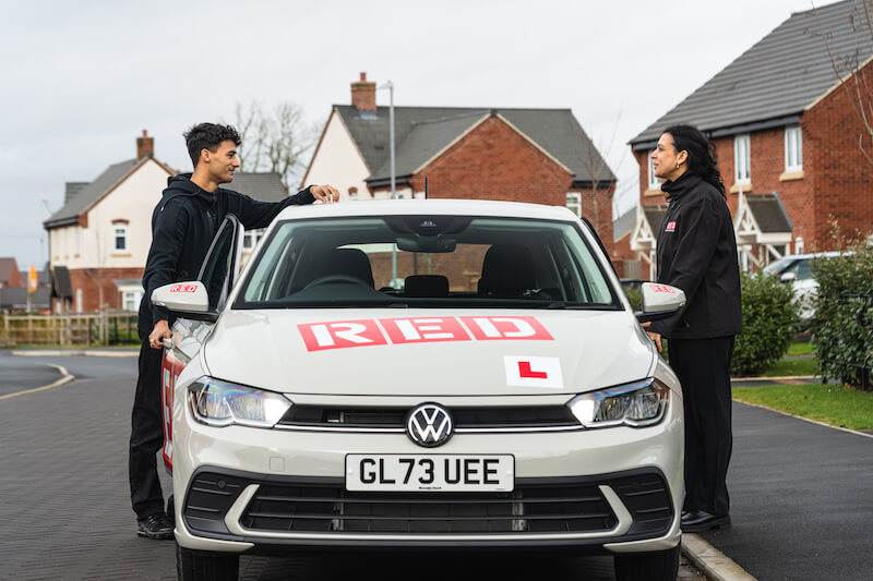 RED driving school car on road